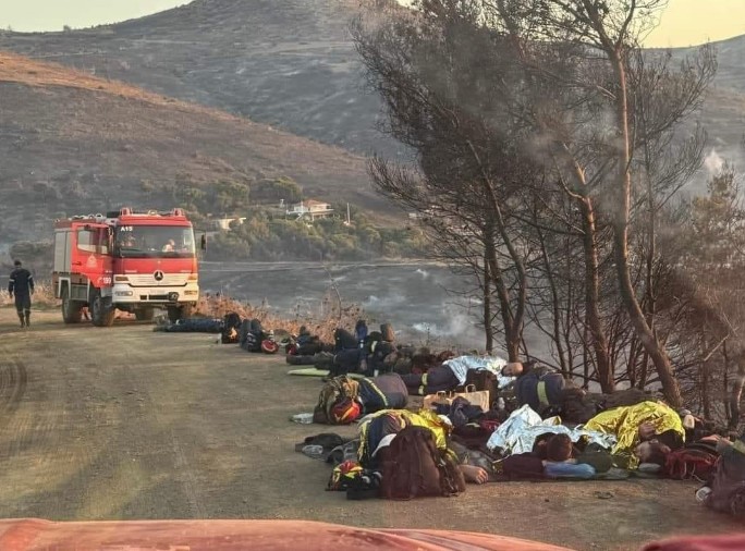 Εξαντλημένοι πυροσβέστες ξαπλώνουν στο χώμα 